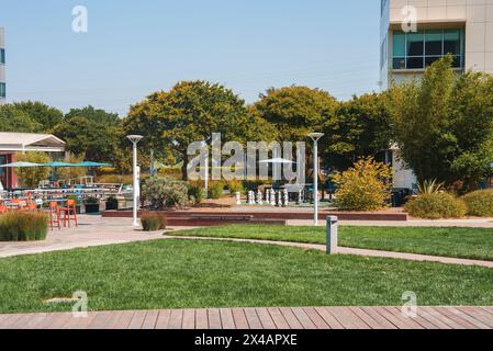 Modern urban park with chess set, tables, and lush landscaping in corporate campus setting. Stock Photo