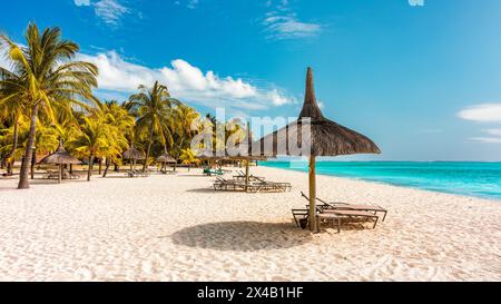 A beach with palm trees and umbrellas on Le morne Brabant beach in Mauriutius. Tropical crystal ocean with Le Morne beach and luxury beach in Mauritiu Stock Photo