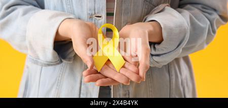 Woman holding yellow ribbon, closeup. Banner for Sarcoma Cancer Awareness Month Stock Photo