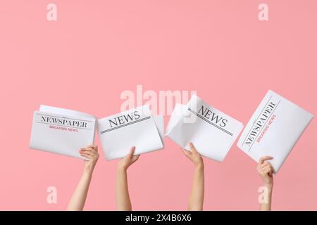Female hands with newspapers on pink background Stock Photo