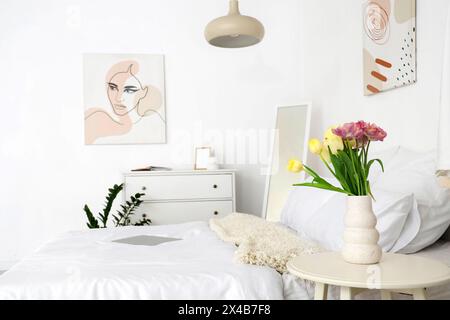 Vase with beautiful tulips on table in light bedroom interior Stock Photo