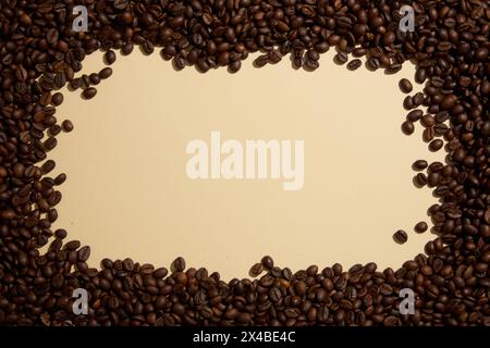 Roasted coffee beans are decorated on a beige background, creating space in the middle for product display or text design. Top view, minimal backgroun Stock Photo