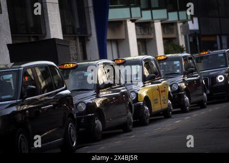 File photo dated 18/11/20 of a queue of black cabs outside Victoria Station, London. A group of more than 10,000 black cab drivers is suing Uber after accusing it of breaching taxi-booking rules in London, in a move which could cost the ride-hailing giant more than £250 million. A group action claim has been filed in the High Court over Uber's operations in the capital between May 2012 and March 2018. Issue date: Thursday May 2, 2024. Stock Photo