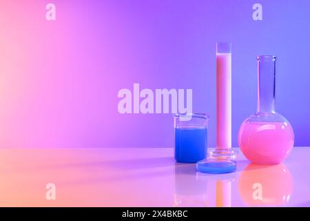 Background of scientific glassware for chemical colorful liquid inside decorated on pink and purple background. Lab theme and blank space for display Stock Photo