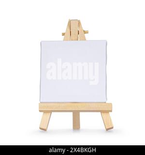 Tiny wooden painters easel with emtpy white canvas, standing facing front. Isolated on a white background. Stock Photo