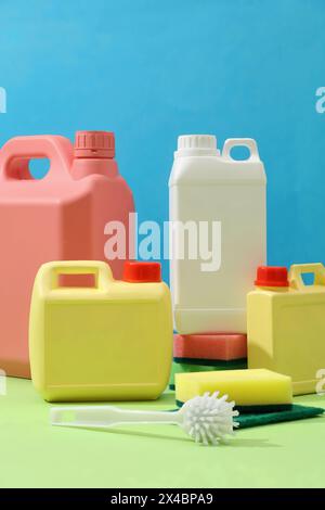 Front of plastic canisters with different sizes and colors decorated on blue background with cleaning tools. Mockup canister empty label for design. H Stock Photo