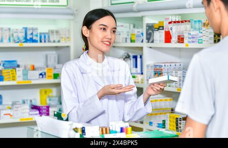 Female pharmacist holding medicine box giving advice to customer in pharmacy store Stock Photo