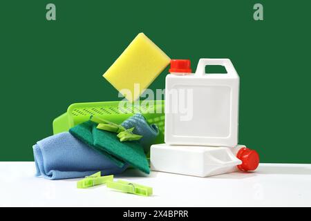 Creative ideas for advertising cleaning services and specialized detergents. White bottles with sponges, wiper and clothespin displayed on a green bac Stock Photo