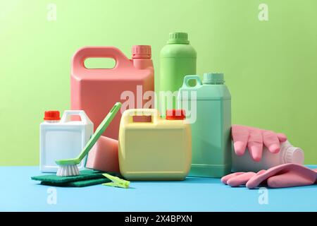 Cleaning products placed on a green background with empty bottles mockup for detergent product, rubber gloves, brushes and sponges. Creative ideas for Stock Photo