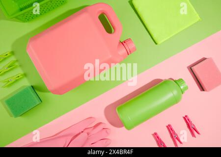 Creative background for advertising cleansing products with pink and green color. Empty bottle and plastic canister of detergents, scouring pads, rubb Stock Photo