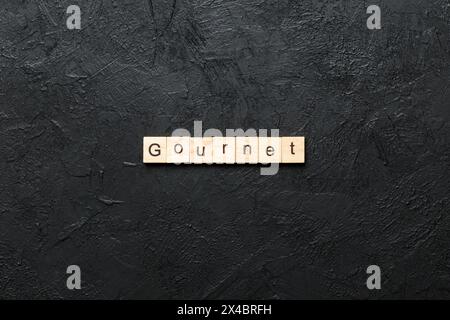 gourmet word written on wood block. gourmet text on cement table for your desing, concept. Stock Photo