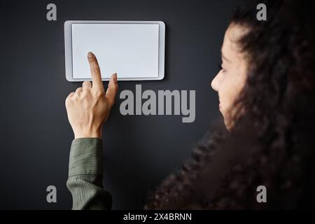 Closeup of young biracial woman adjusting indoor temperature with use of smart home system Stock Photo