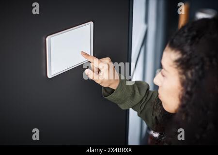 Closeup of young biracial woman tapping on home automation control panel screen, copy space Stock Photo