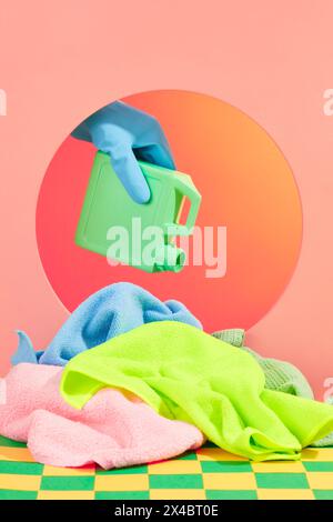 On the color background, a hand holding a plastic container and slowly pouring detergent onto a pile of wipes and preparing to clean. Cleaning product Stock Photo