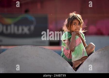 Poor girl sitting on a wall, Pushkar, Rajasthan, India Stock Photo