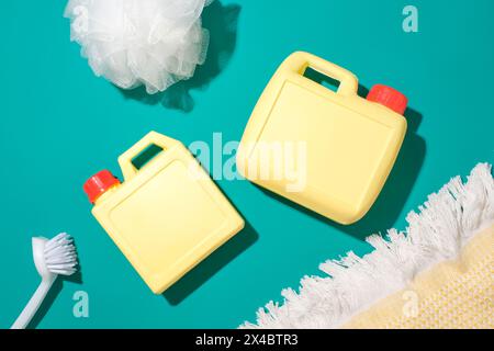 Two unlabeled yellow bottles of detergent, a toilet brush and a bath sponge stand out against the turquoise background. Mockup of house cleaning produ Stock Photo