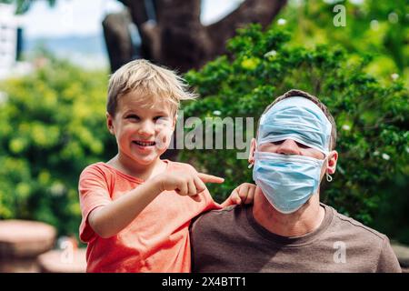 Father and little son hugging, making faces, show a tongue, open mouth, funny plays. Happy childhood. Stock Photo
