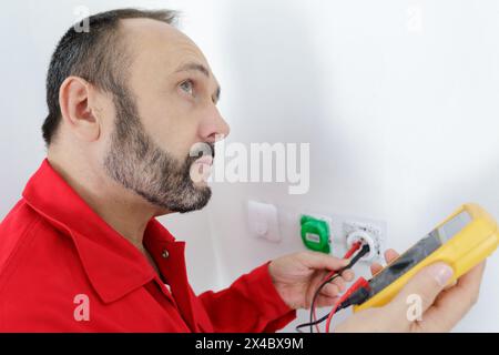 electrician checking socket voltage using multimeter Stock Photo