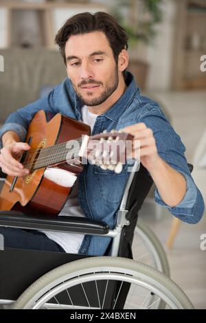 disabled man playing guitar at home Stock Photo