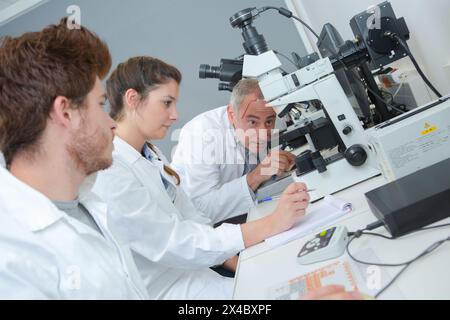 teacher with students using microscope in science class Stock Photo