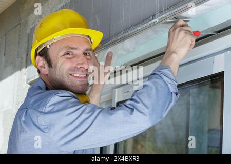 construction worker putting sealing foam tape on window in house Stock Photo