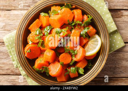 Vegetarian carrot salad with cilantro, spices, lemon juice and olive oil close-up in a plate on a wooden table. Horizontal top view from above Stock Photo