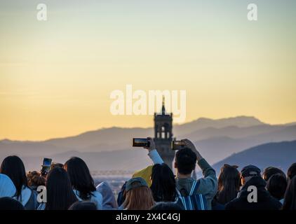 A crowd of tourists holding phones over their heads to take photos of the Florence skyline at Piazzale Michelangelo. An example of overtourism. Stock Photo