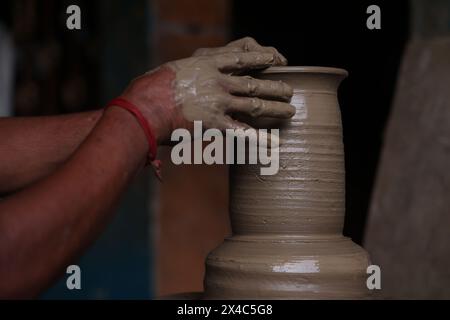 The potter works on a pottery wheel to made of soft colored clay, retro style toned Clay pots with hand and equipment Stock Photo