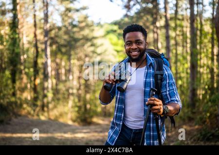 Young man enjoys using  binoculars and hiking  in nature. Stock Photo