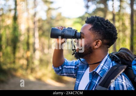 Young man enjoys using binoculars and hiking in nature. Stock Photo