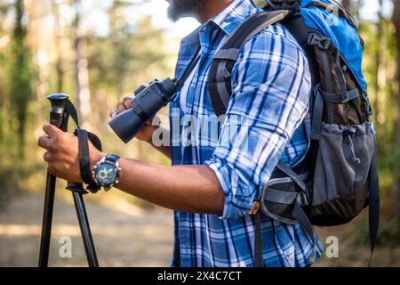 Young man enjoys using  binoculars and hiking  in nature. Stock Photo