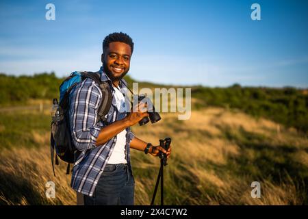 Young man enjoys using binoculars and hiking in nature. Stock Photo