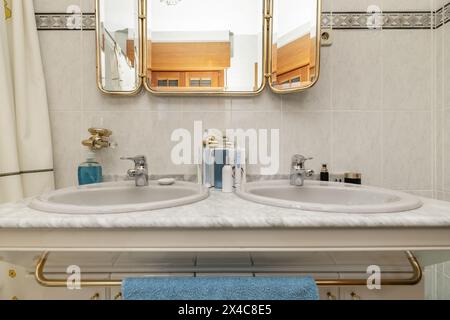 Old bathroom with two sinks integrated into the marble countertop and triptych mirror Stock Photo