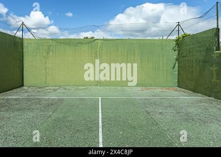 Fences and a green pediment wall in a yard with worn floors on a nice sunny day Stock Photo