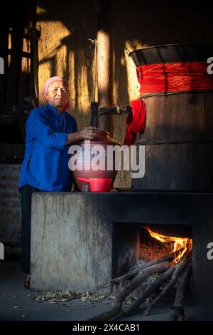 Hmong woman pouring rice wine from a barrel, Bac Ha, Lao Cai Province, Vietnam Stock Photo