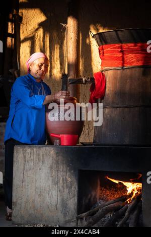 Hmong woman pouring rice wine from a barrel, Bac Ha, Lao Cai Province, Vietnam Stock Photo