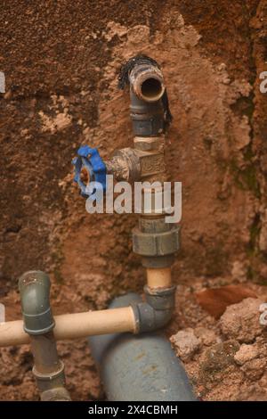 Plumbing pipes passing through a rough concrete wall Stock Photo