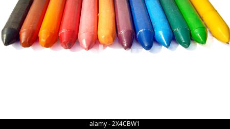A spectrum of colorful wax crayons in a row on an isolated white ...