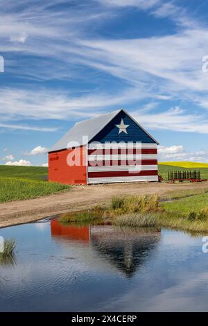 USA, Idaho, Genesee. Barn painted in red, white and blue and reflection in small pond Stock Photo