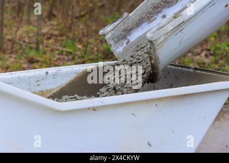 Concrete buggy at construction site is loaded with wet cement from cement truck chute Stock Photo