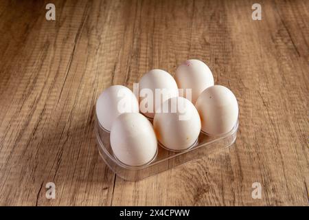 6 white eggs in a plastic holder on a wooden background Stock Photo