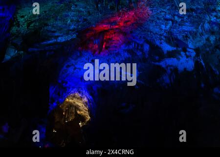 Prometheus karst cave, illuminated by colorful lights, stalactites and stalagmites. Stock Photo