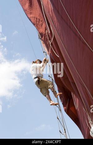 A pirate in full costume climbs a rope ladder on the Jolly Rover tall ship, which is docked on the riverfront in Georgetown, South Carolina, USA. Stock Photo