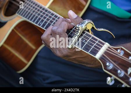 Mans hand is playing guitar, focus on fingers and mediator, close up Stock Photo
