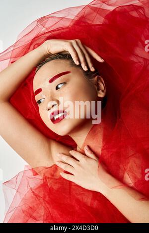 Asian woman in red dress poses with hands on head. Stock Photo