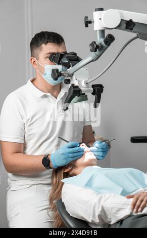 A modern dentist who uses advanced technologies in his practice treats the patient under a microscope to ensure the highest quality of the result and Stock Photo