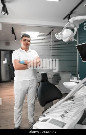 A doctor stands near a professional dental chair. The modern dental clinic provides teeth whitening and straightening services for patients of all Stock Photo