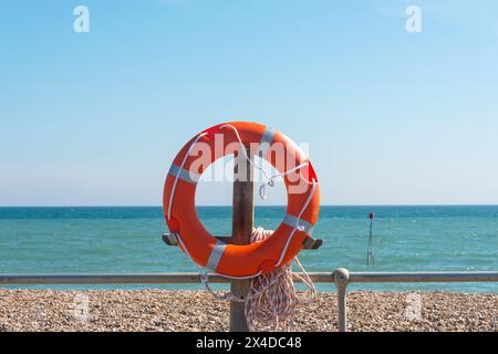 lifebouy, orange lifebouy by a beach and sea with blue sky Stock Photo