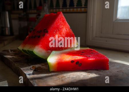 The fresh colorful watermelon on the kitchen table, partially lightened by the window sunlight. Stock Photo