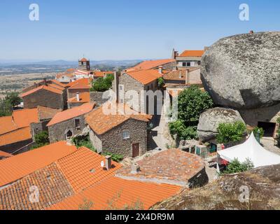 View over the roof tops of the ancient Portuguese village built on the side of a mountain between large boulders with cobblestone streets and houses. Stock Photo